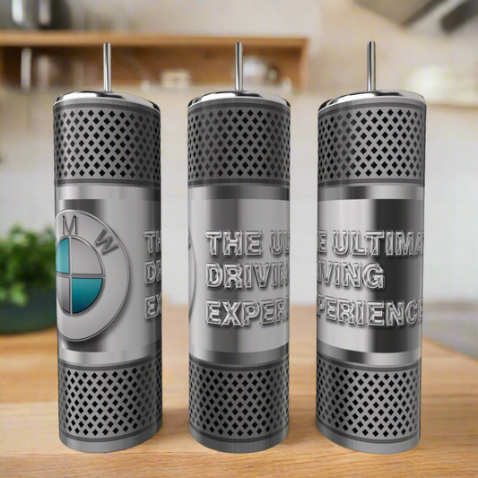 Three Kreative Kreationz Car Enthusiast Silver Stainless Steel 20oz Tumblers are shown; one features a BMW logo, and the others read "THE ULTIMATE DRIVING EXPERIENCE." A blurred kitchen is visible in the background.