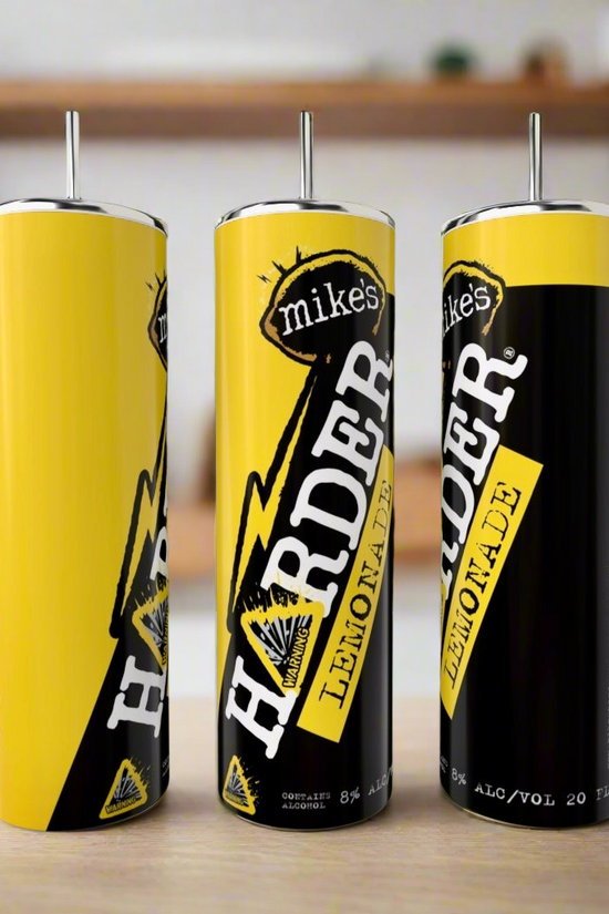 Three 20oz Mikes Harder Lemonade | Variety Tumblers by Kreative Kreationz, each with sleek metal straws, sit on a countertop with a blurred kitchen and shelves in the background.