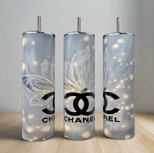 Three Kreative Kreationz CC 20oz Skinny Tumblers with butterfly designs showcase a sleek silver and white palette. Made from double-wall stainless steel, these luxury beverage tumblers rest elegantly on a light wooden surface against a neutral background.