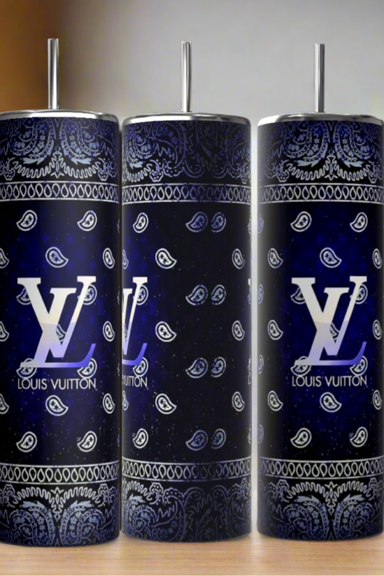 Three Kreative Kreationz Louis Vuitton Blue Ombre 20oz Tumblers with metal straws sit on wood. Each features a blue paisley bandana pattern and bold white Louis Vuitton logos, offering a chic, modern look against a softly blurred background.