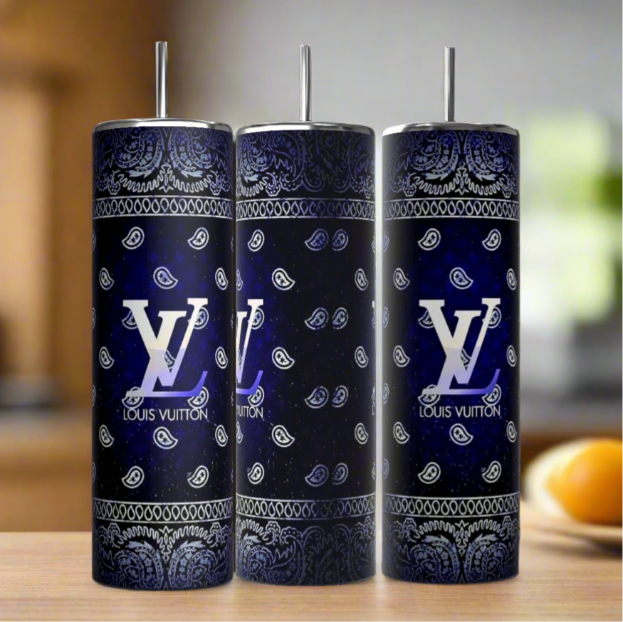 Three Kreative Kreationz Louis Vuitton Blue Ombre 20oz Tumblers with metal straws sit on wood. Each features a blue paisley bandana pattern and bold white Louis Vuitton logos, offering a chic, modern look against a softly blurred background.