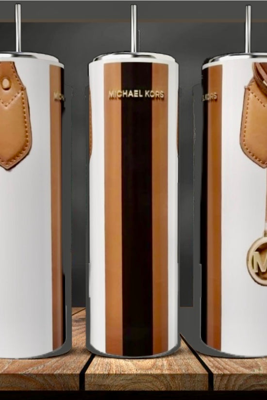 Three tall, glossy Kreative Kreationz MK | White 20oz Tumblers with a metallic gold and white design and brown faux leather details are displayed on a wooden surface against a dark background.