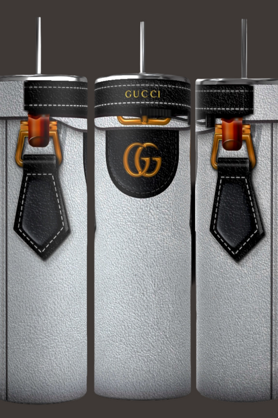Introducing the GUCCI Purse Inspired 20oz Tumbler by Kreative Kreationz: This elegant set of three cylindrical silver tumblers showcases designs inspired by a GUCCI designer purse. Featuring black leather strap motifs and the famous Gucci logo with striking gold and black details, each tumbler is crafted for durability and comes with a metal straw on top, making them stand out beautifully against any dark backdrop.