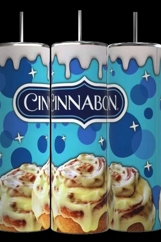 Three Kreative Kreationz Cinnabon 20oz Tumblers with Removable Lid Toppers, designed with whipped cream accents, stand side by side. The blue background showcases the Cinnabon logo and features illustrations of signature cinnamon rolls with icing dripping down the sleek design of each tumbler.