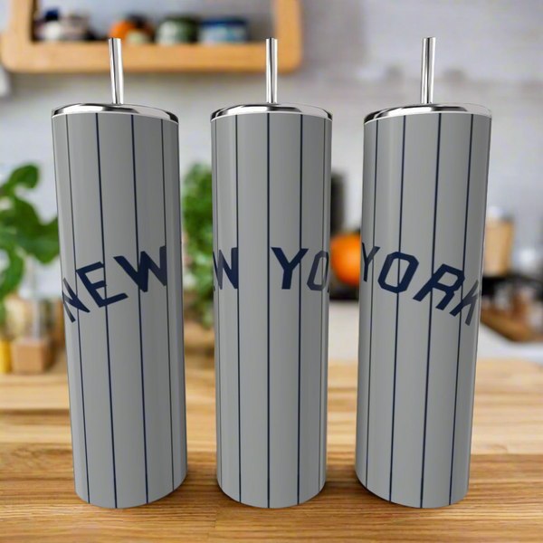 Three tall Kreative Kreationz New York Yankees Grey 20oz Tumblers with silver finish and blue "NEW YORK" lettering stand on a wooden counter—an ideal set for Yankees fans.