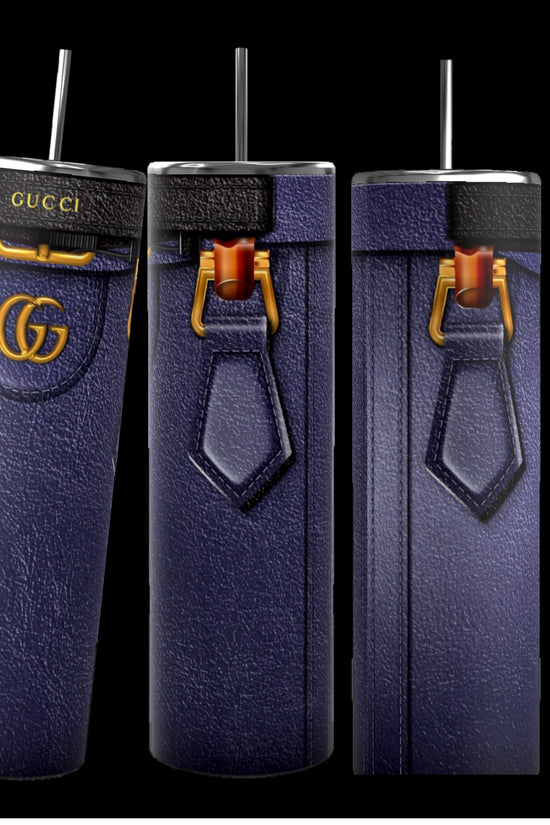 Three tall, cylindrical Gucci Diana-inspired purple tumblers from Kreative Kreationz, featuring a leather-like texture, gold Gucci logos, and black straws, stand on a cobblestone street. With durable construction and a 20 oz capacity, the focus remains on these stylish and luxurious cups against the softly blurred background.