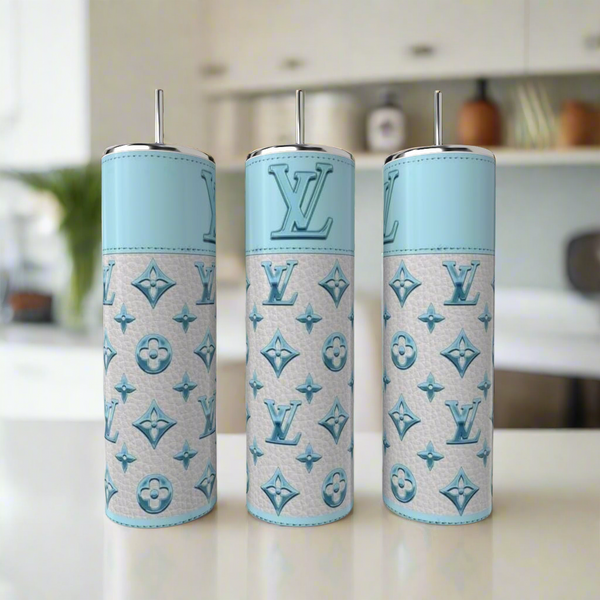 Three LV Sky Blue 20oz Tumblers by Kreative Kreationz, featuring a luxury-inspired light blue and white design with metal straws, are displayed on a white countertop in a modern kitchen.