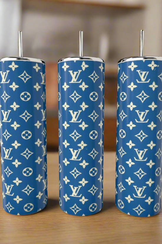 Three LV Blue & Yellow 20oz Tumblers by Kreative Kreationz, featuring a white Louis Vuitton monogram pattern and silver straws, are displayed on a wooden surface against a blurred indoor background.