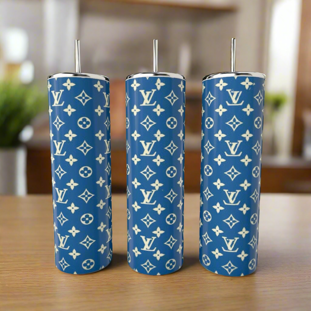 Three LV Blue & Yellow 20oz Tumblers by Kreative Kreationz, featuring a white Louis Vuitton monogram pattern and silver straws, are displayed on a wooden surface against a blurred indoor background.