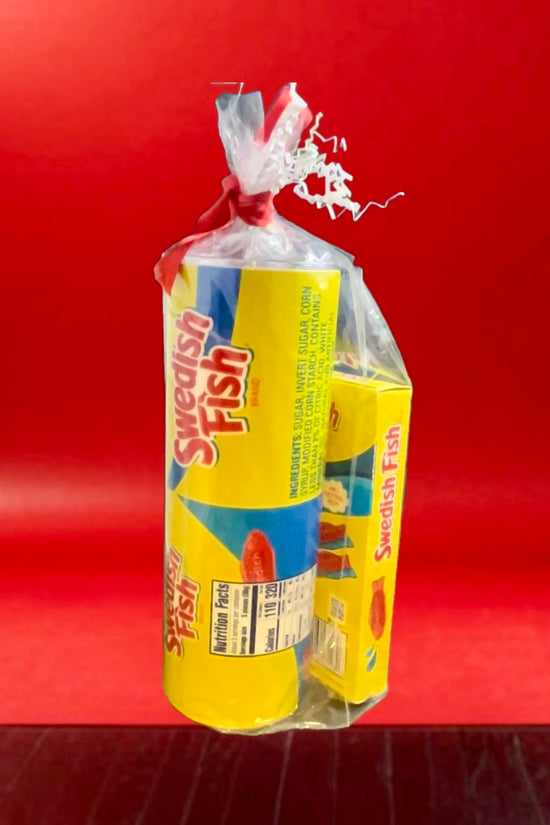 A plastic bag containing a Swedish Fish Gift Set with a 20oz stainless steel skinny tumbler, featuring yellow and blue packaging, branded 