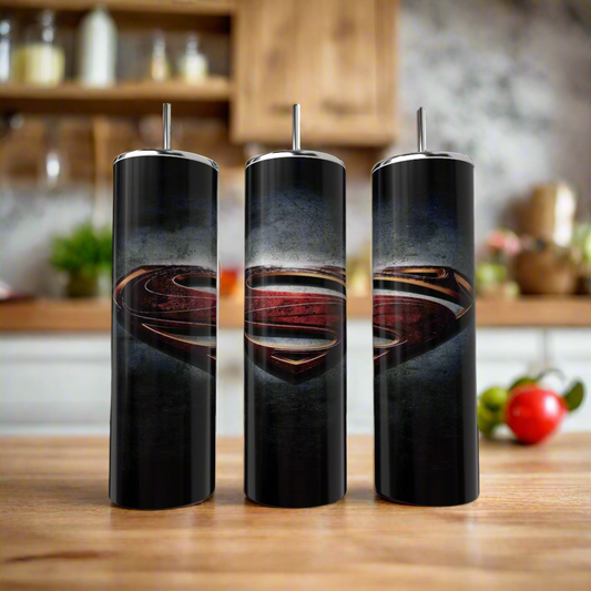 Three Kreative Kreationz Superman Smokey 20oz Tumblers with straws and a bold dark Superman logo are displayed on a wooden kitchen counter, with shelves and produce softly blurred in the background.