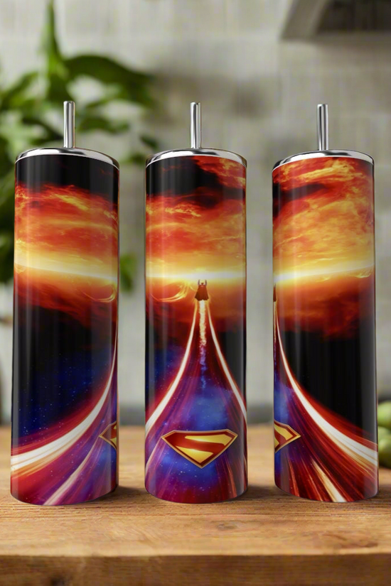 Three Kreative Kreationz Superman Fireball 20oz Tumblers with straws showcase vibrant designs and swirling skies, displayed on a wooden surface—ideal as reusable tumblers or in a stylish gift box tumbler set.