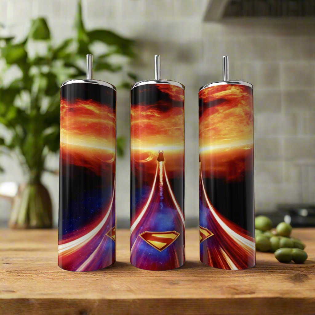 Three Kreative Kreationz Superman Fireball 20oz Tumblers with straws showcase vibrant designs and swirling skies, displayed on a wooden surface—ideal as reusable tumblers or in a stylish gift box tumbler set.