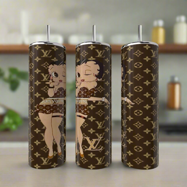 Three Betty B LV 20oz Skinny Tumblers from Kreative Kreationz, crafted in stainless steel with a luxury-inscribed design and an animated character, are showcased on a kitchen counter. The unique tumblers feature iconic logos paired with the beloved Betty Boop in a playful pose.