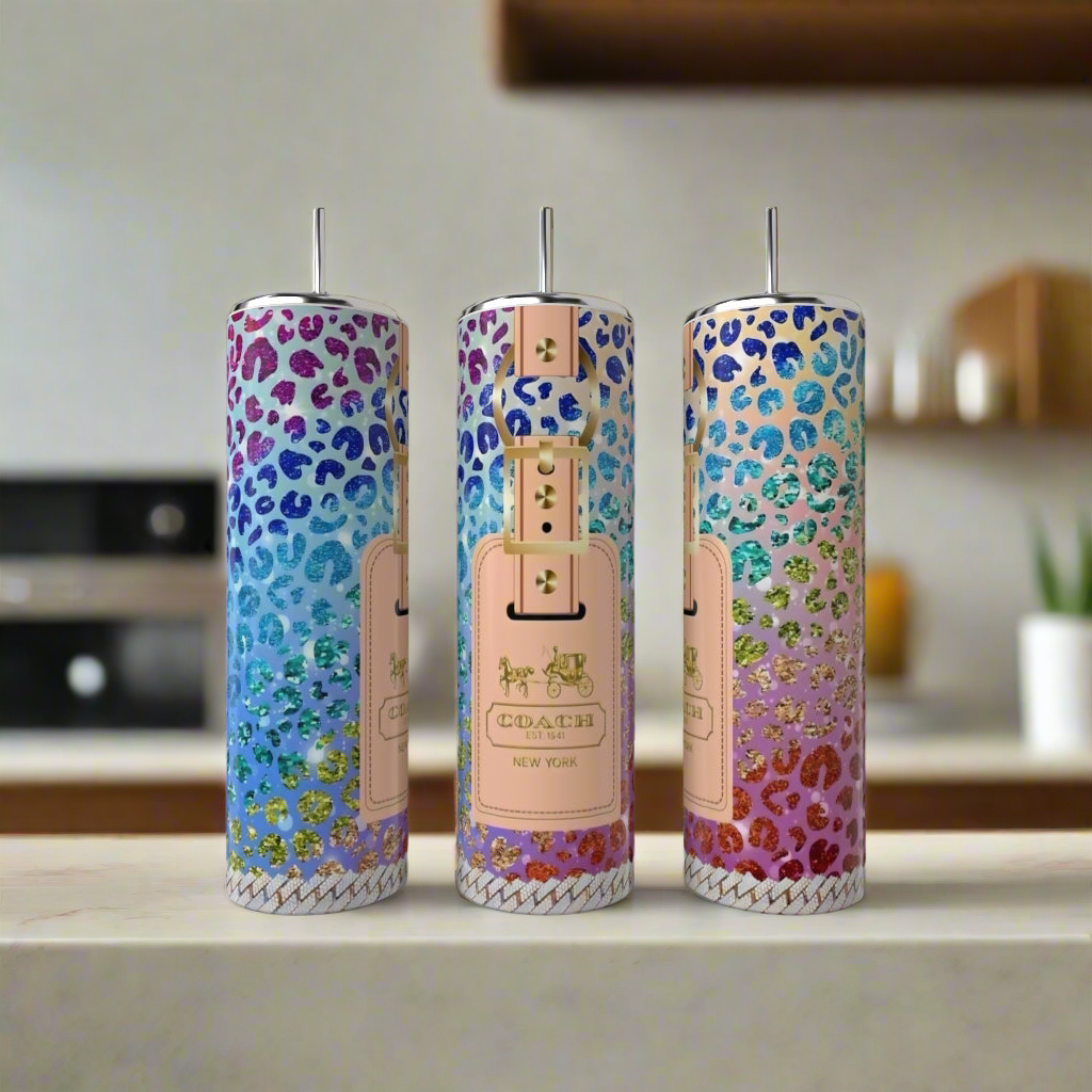 Three tall, skinny tumblers with colorful, glittery leopard print patterns and a "Kreative Kreationz" label stand on a kitchen counter, resembling chic designer drinkware. Product: Minnie Mouse LV Peek-a-Boo 20oz Skinny Tumbler.