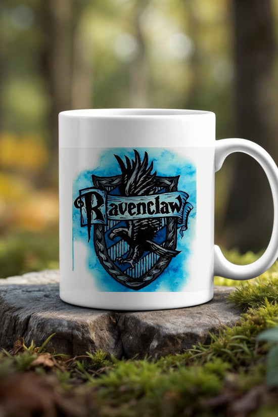 The Ravenclaw Ceramic Mug by Kreative Kreationz features a blue crest design and sits on a tree stump outdoors, blending with greenery and trees—an eco-friendly choice for any Harry Potter fan.