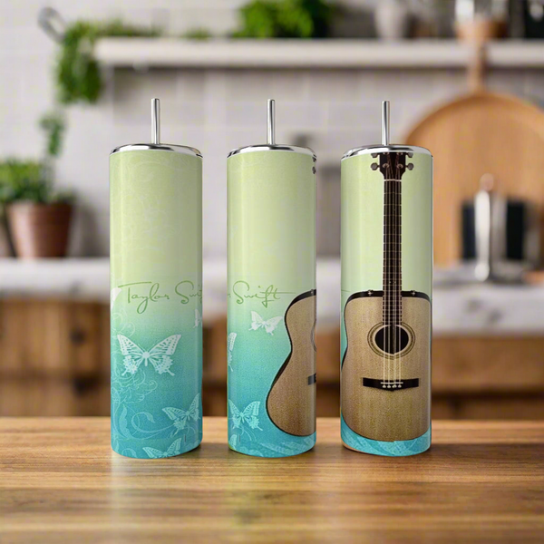 Three Kreative Kreationz "Debut Guitar Taylor Swift" 20oz stainless steel tumblers with butterfly designs and guitars sit on a wooden counter—eco-friendly, reusable, and perfect for your kitchen.
