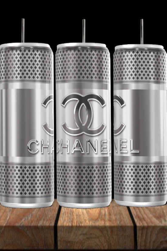 Three Kreative Kreationz Chanel Silver Stainless Steel 20oz tumblers with straws, textured design, and interlocking C’s logo are shown on wood against a black background—a true luxury drinkware statement.