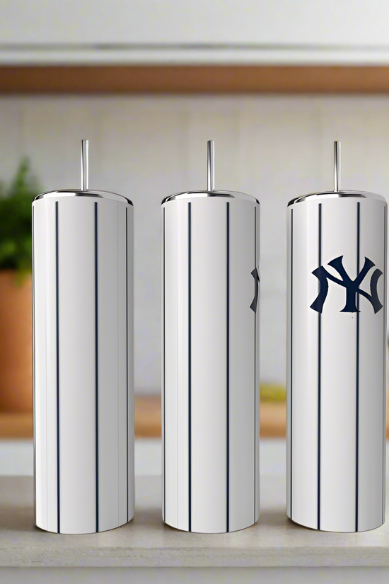 Three stainless steel tumblers with vertical pinstripes and metal straws by Kreative Kreationz are on a kitchen counter. The rightmost tumbler is the New York Yankees 20oz Tumbler with a dark blue Yankees-style logo.