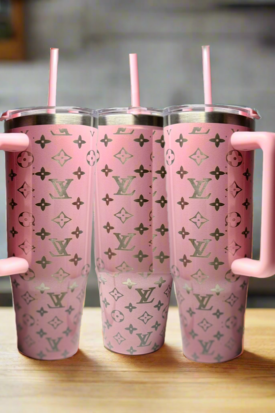 Three Kreative Kreationz Pink 30oz Engraved Tumblers, each with a large handle, pink straw, and silver monogram pattern, are lined up on a wooden kitchen surface.