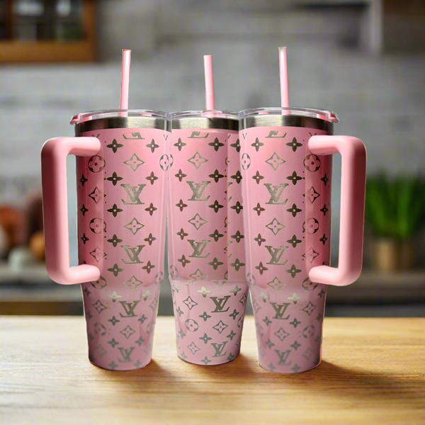 Three Kreative Kreationz Pink 30oz Engraved Tumblers, each with a large handle, pink straw, and silver monogram pattern, are lined up on a wooden kitchen surface.