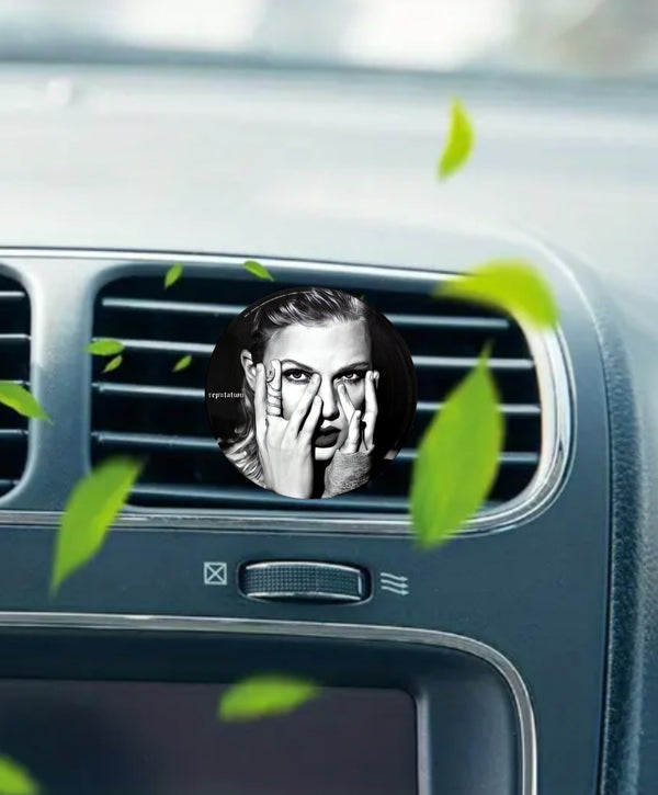 The REPUTATION Taylor Swift Car Air Freshener by Kreative Kreationz features a vinyl record design with a black-and-white portrait of Taylor Swift, partially covering her face with her hands and green leaves floating around.