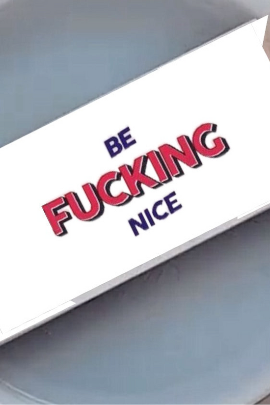 Close-up of a round, gray-colored object with a rectangular card attached to a stick in the middle. The card has the words 