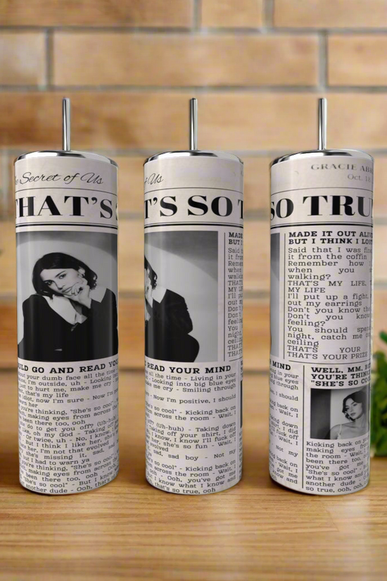 Three Gracie Abrams 20oz Skinny Tumblers by Kreative Kreationz, with pump tops and a vintage column design, rest on a wooden surface; green herbs are to the right, and a tiled wall is in the background.