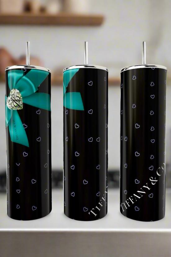 Three sleek, black Kreative Kreationz Tiffany Hearts 20oz Tumblers display small blue heart patterns. One features a large blue bow with a silver heart. Made from eco-friendly stainless steel, the words 