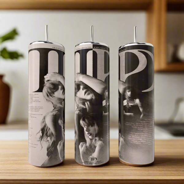 Three tall, cylindrical Kreative Kreationz TTPD 20oz Tumblers feature luxury-inspired designs with black-and-white images of women in hats. Elegantly placed on a wooden surface, they blend beautifully with a blurred background of shelves and plants.