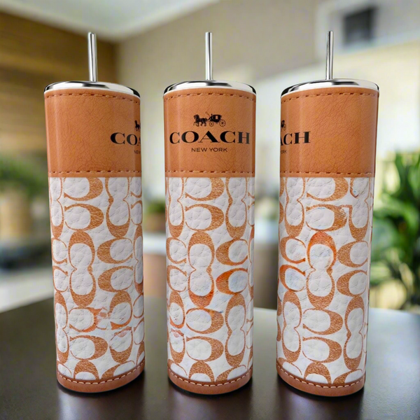 Three tall, cylindrical 20oz tumblers by Kreative Kreationz are lined up on a table. Each features a brown leather-like design with white patterns and the "COACH NEW YORK" logo against a blurred background.