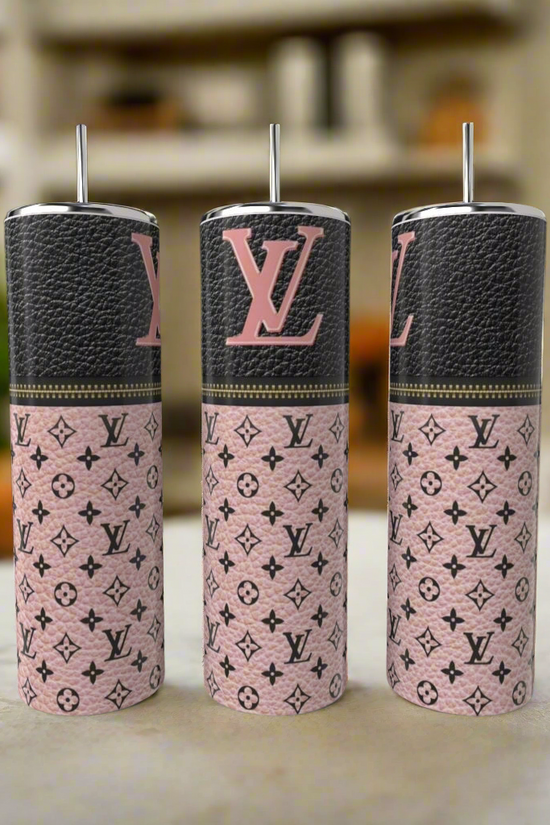 Three Kreative Kreationz LV Blush Pink 20oz Tumblers with metal straws are displayed on a countertop. Featuring a luxury-inspired monogram design, each stainless steel tumbler adds style to your drinkware. A blurred kitchen is in the background.