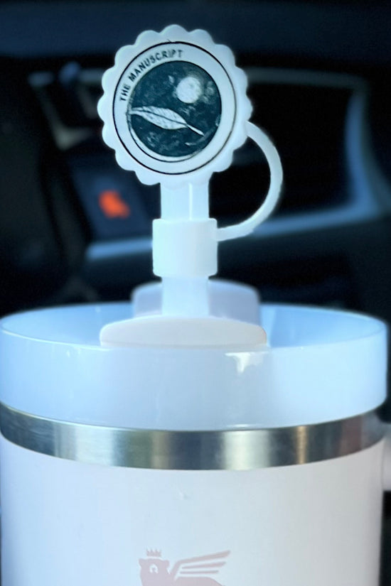 A white cup with a handle displays a round sticker on the lid, which features an illustration of a planet and spacecraft, accompanied by the text 