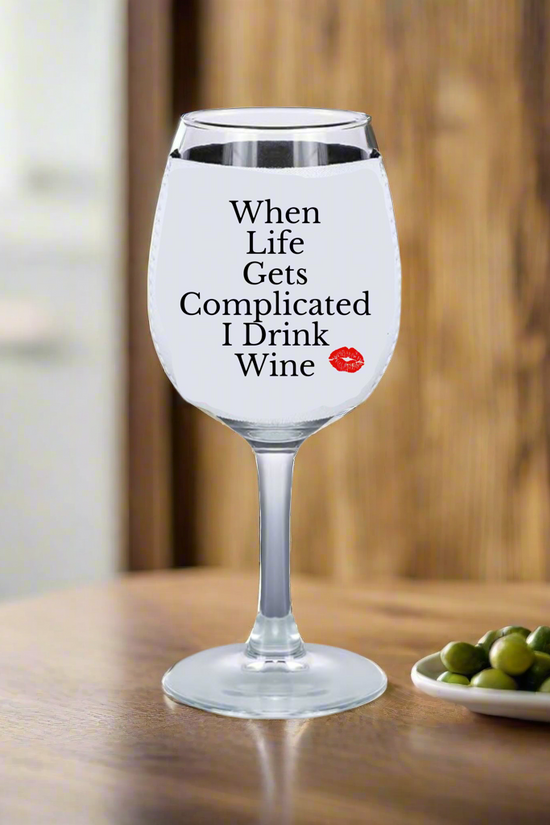 A wine glass with white liquid rests on wood, featuring 