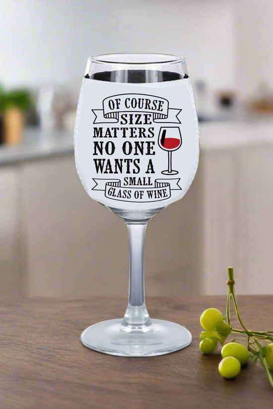 On a kitchen counter, a wine glass displays funny text about size: 