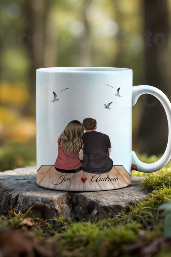 The Personalized Couples Ceramic Mug by Kreative Kreationz features an illustration of a couple on a dock with birds in the background. 