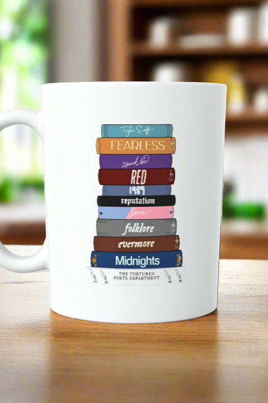 The Taylor Swift Era’ Book Ceramic Mug by Kreative Kreationz features vibrant book spines titled after Taylor Swift albums, making it a perfect gift for any Swiftie. The eye-catching design stands out in any kitchen.