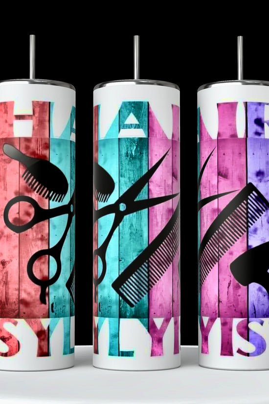 Three cylindrical tumblers from the Hairstylist Collection by Kreative Kreationz are displayed against a black background. Each 20oz tumbler showcases a pattern of various hairstyling tools, including scissors, clippers, combs, hairdryers, mirrors, and pink roses on a black background. Experience durable construction with every use.