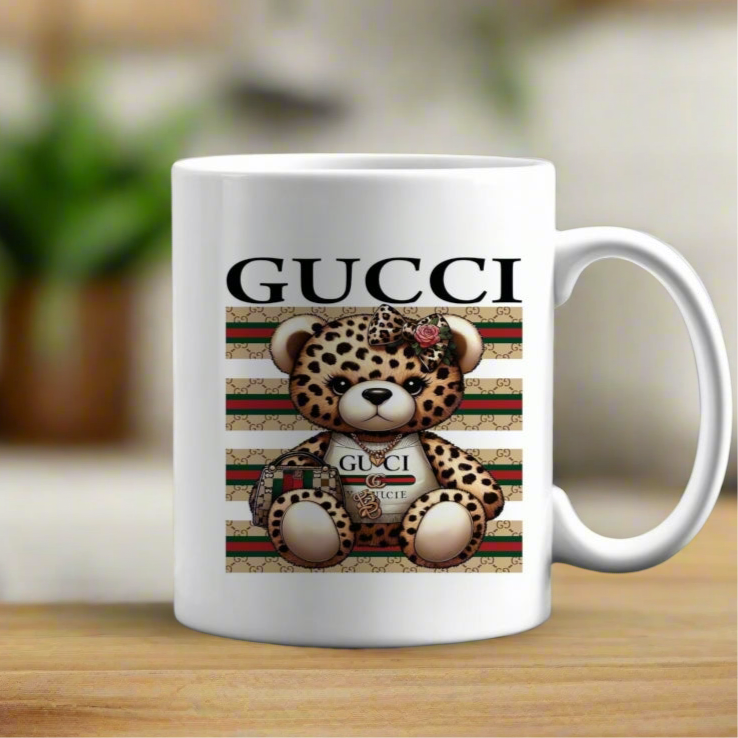 The Kreative Kreationz Ceramic Mug features a cute plush leopard holding a Gucci handbag with "GUCCI" text above, set against a green, red, and beige patterned background. Perfect for coffee lovers.