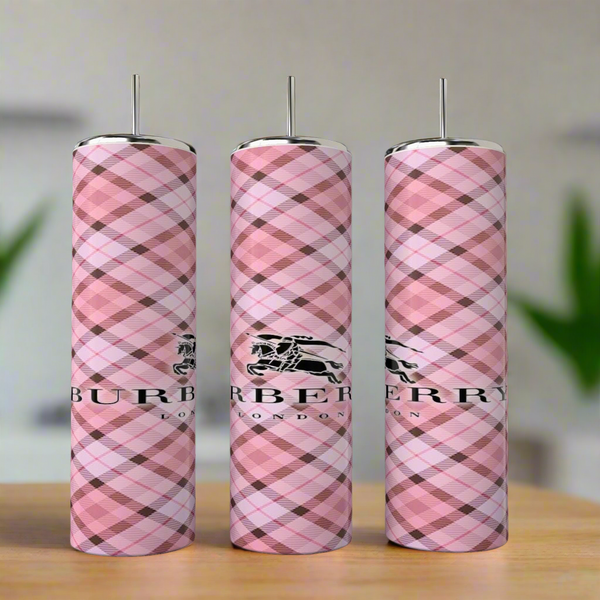 Three tall, cylindrical Burberry 20oz Skinny Tumblers by Kreative Kreationz stand upright with a pink plaid pattern and Burberry London logo, displayed on a blurred indoor background with greenery—ideal for any luxury tumbler collection.
