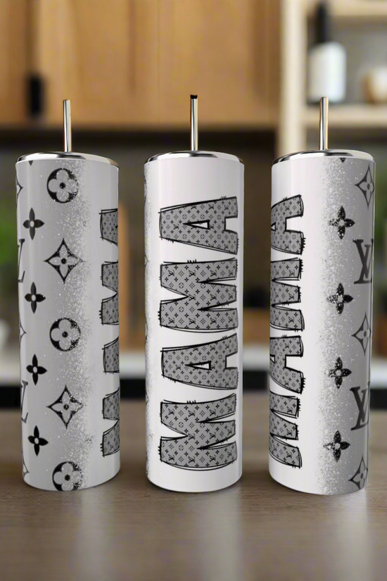 Three 20oz white cylindrical stainless steel tumblers from Kreative Kreationz, each with metal straws and unique designs, sit against a blurred kitchen backdrop. Two have luxury-inspired patterns, while the center tumbler reads 