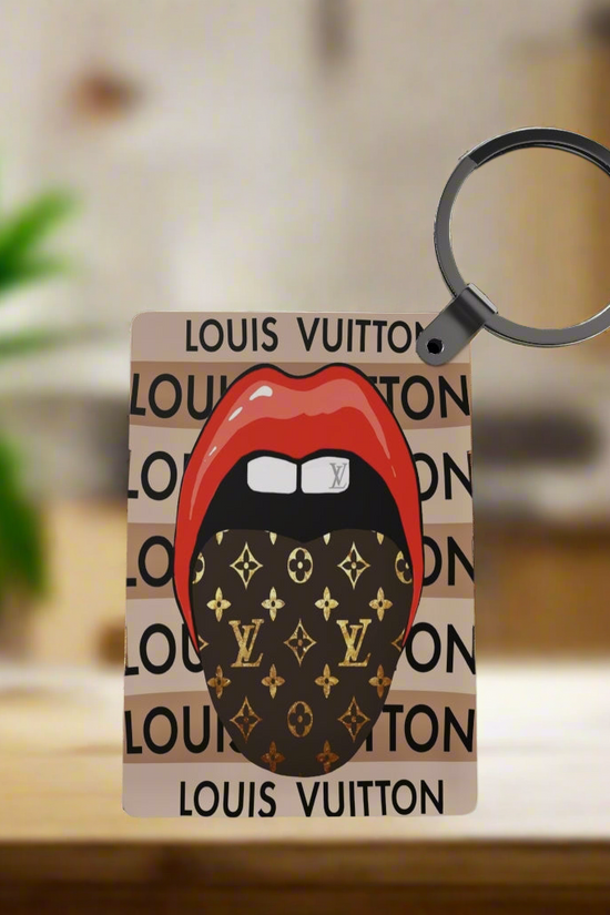 The LV Inspired Keychain by Kreative Kreationz features red lips and a black Louis Vuitton patterned face mask on a repeating logo background, adding a stylish touch to your everyday accessories.