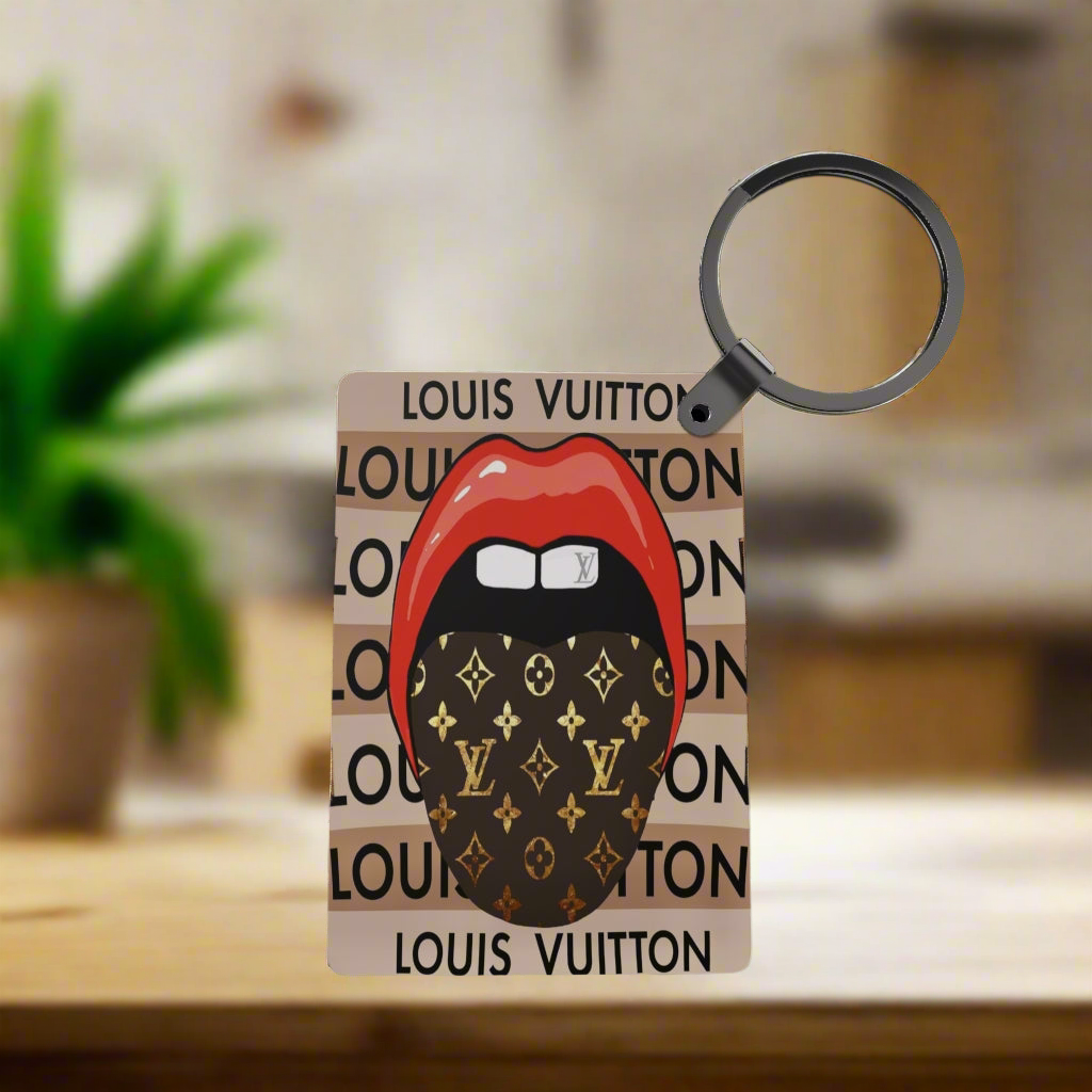 The LV Inspired Keychain by Kreative Kreationz features red lips and a black Louis Vuitton patterned face mask on a repeating logo background, adding a stylish touch to your everyday accessories.