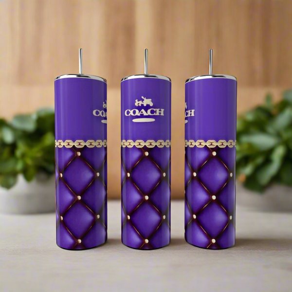 Three Coach 20oz Skinny Tumblers by Kreative Kreationz feature a quilted design with gold chain accents and the "COACH" logo. These tall, purple tumblers with silver lids and straws exude elegance and functionality and are set against a backdrop of blurred green plants.