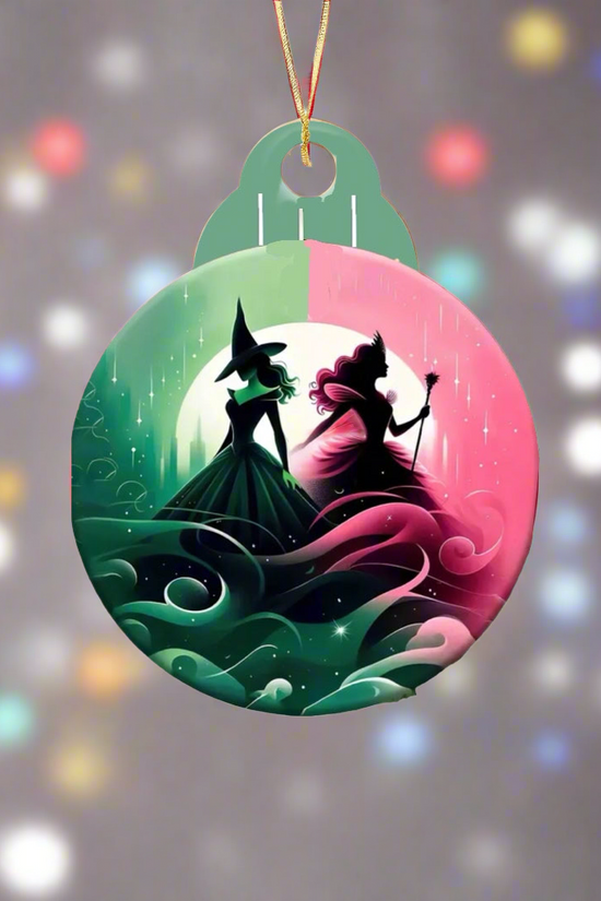 Introducing the Wicked Christmas Tree Ornament from Kreative Kreationz: a stunning round creation featuring a sublimated design of two witch silhouettes—one in green, the other in pink—set against an enchanting moonlit, swirling background. It elegantly suspends from a string amid the glow of colorful holiday lights.
