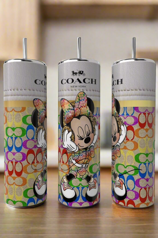 Three Minnie Mouse Coach 20oz Skinny Tumblers by Kreative Kreationz, featuring colorful designs with a bow-wearing cartoon mouse and Coach branding, stand on a kitchen wooden surface with blurred cabinets and plants in the background.