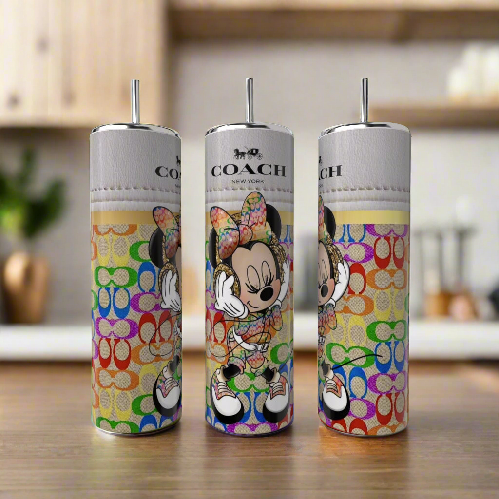 Three Minnie Mouse Coach 20oz Skinny Tumblers by Kreative Kreationz, featuring colorful designs with a bow-wearing cartoon mouse and Coach branding, stand on a kitchen wooden surface with blurred cabinets and plants in the background.