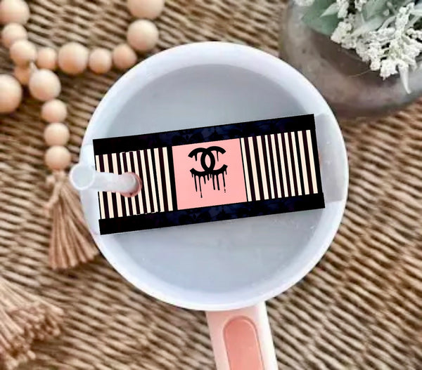A round white cup with a pink handle sits on a woven surface, topped with the Chanel | Stanley Lid Plate/Topper by Kreative Kreationz, featuring beaded and floral accents—perfect for styling your Stanley tumbler.
