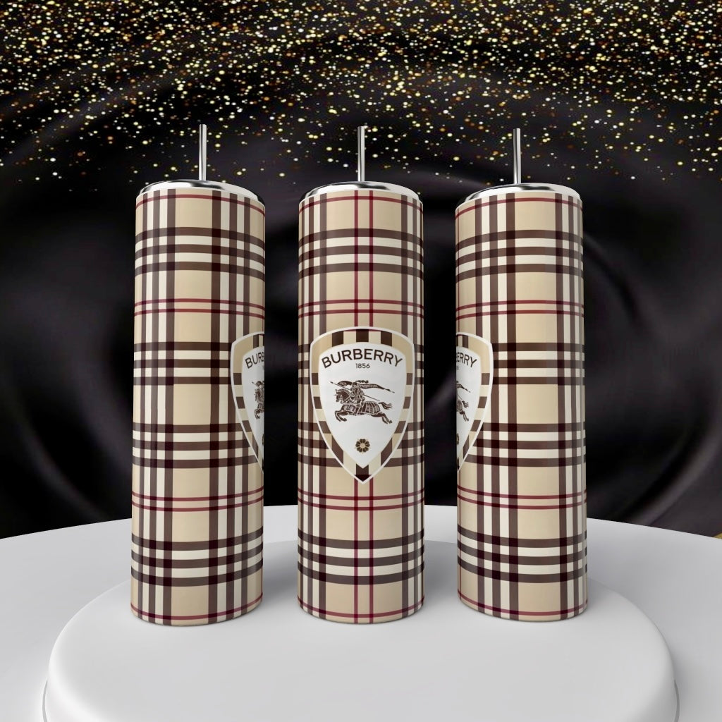 Three cylindrical Kreative Kreationz Burberry 20oz Skinny Tumblers, showcasing a signature plaid pattern and logo, stand on a white podium with golden sparkles against black satin—luxury drinkware elevated.
