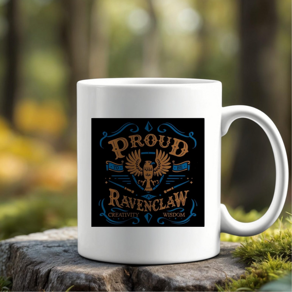 The Proud Ravenclaw Ceramic Mug by Kreative Kreationz rests on a mossy rock outdoors, displaying an eagle and the phrase "Proud Ravenclaw – Creativity, Wisdom" in blue and gold. Its eco-friendly design is set against a blurred forest background.